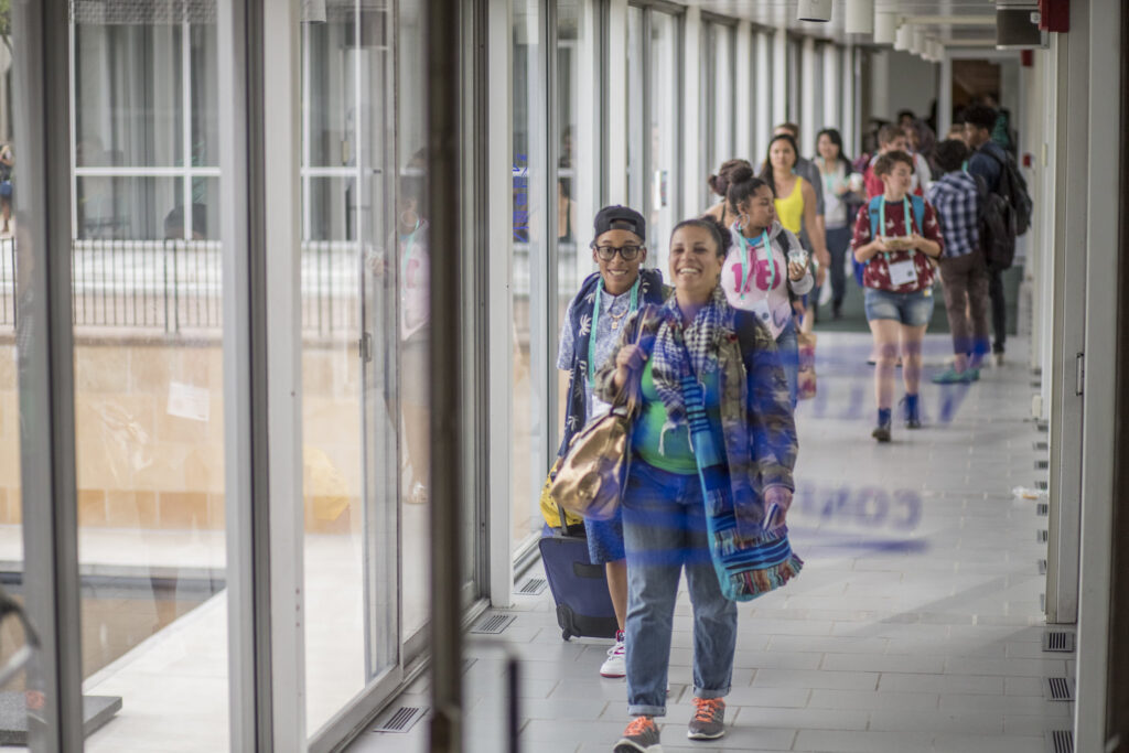 A group of a dozen or more people walking down a hallway during the AMC. They are smiling and wearing colorful clothing.
