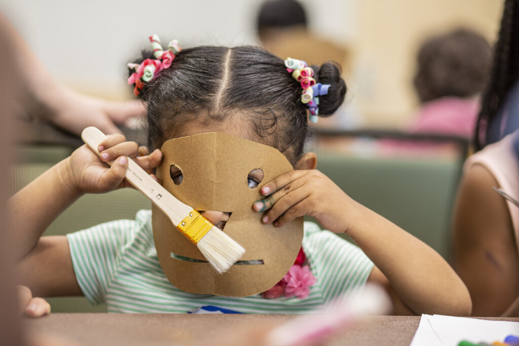 AMC kid playing with cardboard paper mask